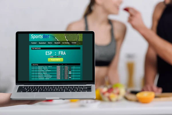 Selective focus of laptop with sportsbet website on screen near couple in kitchen — Stock Photo