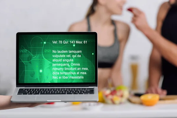 Selective focus of laptop with medical website on screen near couple in kitchen — Stock Photo