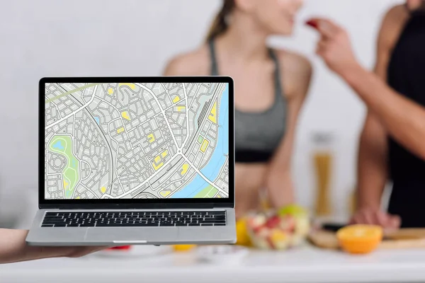 Selective focus of laptop with map on screen near couple in kitchen — Stock Photo