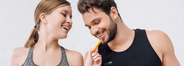 Plan panoramique de fille heureuse nourrissant homme gai avec tranches d'orange — Photo de stock