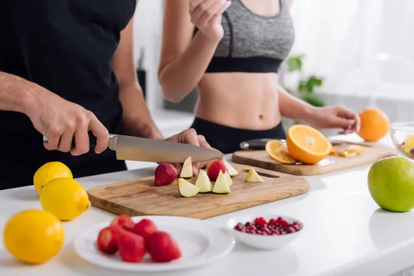 Cropped view of man cutting fruits on cutting board near woman — Stock Photo