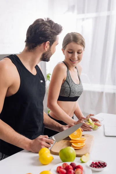 Счастливая женщина рядом с мужчиной с ножом и фруктами — стоковое фото