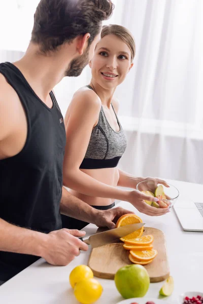 Щаслива жінка дивиться на чоловіка з ножем біля апельсина — стокове фото