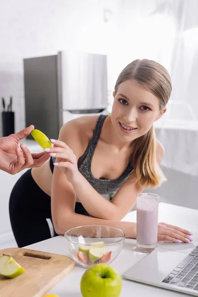 Man giving sliced apple to girl near laptop and glass of smoothie — Stock Photo