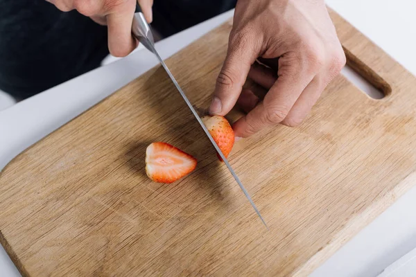 Abgeschnittene Ansicht eines Mannes, der rote Bio-Erdbeeren auf Schneidebrett schneidet — Stockfoto