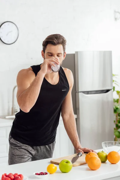 Homem bonito bebendo smoothie perto de frutas frescas — Fotografia de Stock