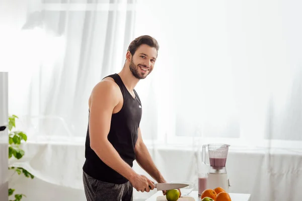 Homem barbudo feliz segurando faca perto de maçã fresca — Fotografia de Stock