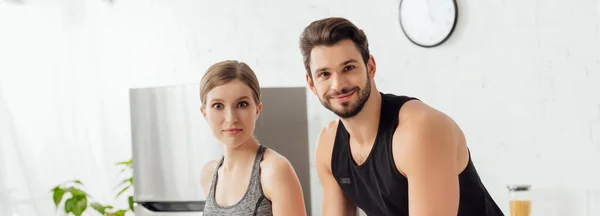 Plan panoramique de couple heureux et sportif regardant la caméra — Photo de stock