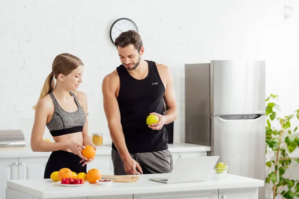 Happy man and woman with fruits near laptop — Stock Photo