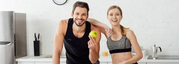 Panoramic shot of happy girl smiling near man with ripe apple — Stock Photo