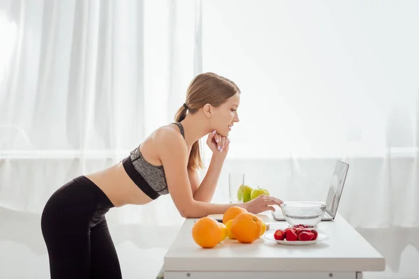 Side view of happy woman in sportswear using laptop — Stock Photo