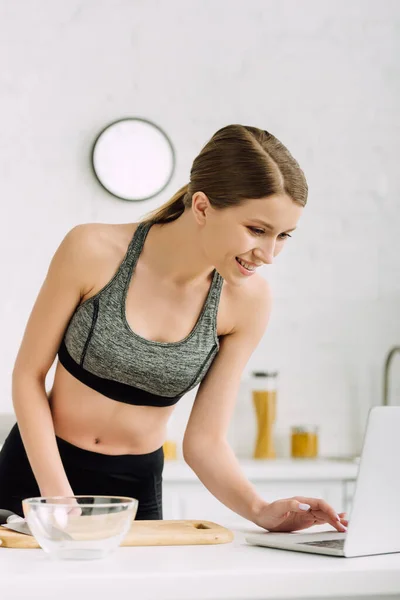 Heureux jeune blogueur en vêtements de sport à l'aide d'un ordinateur portable — Photo de stock