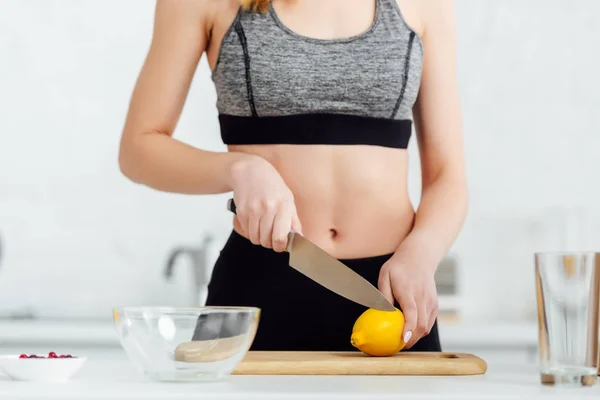 Cropped view of sportive girl cutting lemon — Stock Photo