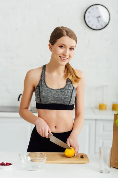 Chica feliz y deportivo cortando limón fresco - foto de stock