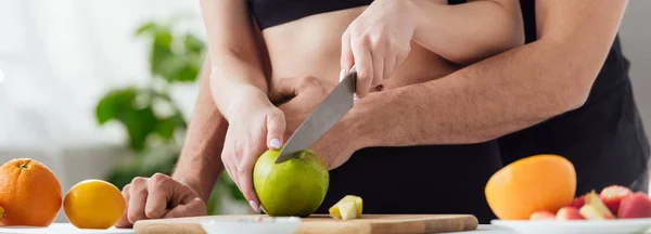 Panoramic shot of couple cutting apple on chopping board — Stock Photo