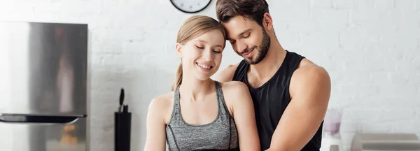 Plano panorámico de feliz pareja sonriendo en la cocina - foto de stock