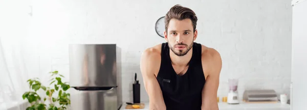 Panoramic shot of sportive man looking at camera at home — Stock Photo