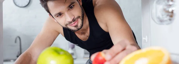 Tiro panorâmico de homem bonito tomando morango da geladeira — Fotografia de Stock