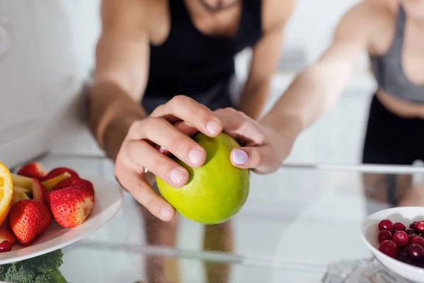Cropped view of man and woman touching apple in fridge — Stock Photo