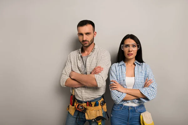 Frustrated manual workers standing with crossed arms on grey — Stock Photo