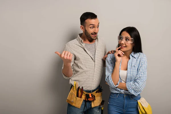 Frightened manual workers talking at pointing on grey — Stock Photo