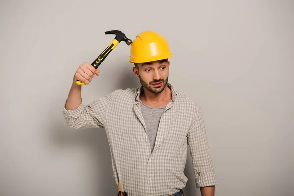 Вдумливий ремонтник у шоломі тримає молоток на сірому — Stock Photo