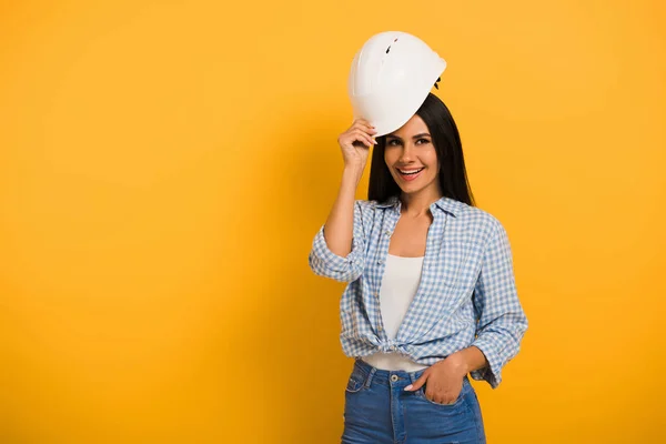 Souriant ouvrière en casque sur jaune — Photo de stock