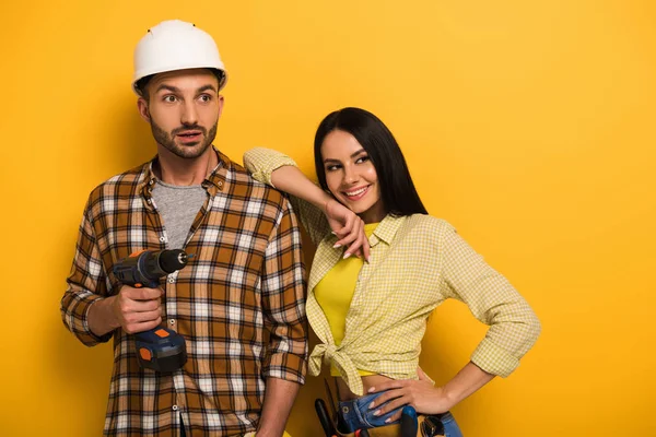 Operai professionisti che tengono trapano elettrico su giallo — Foto stock