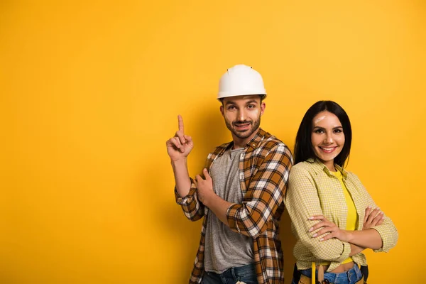 Happy manual workers pointing up on yellow — Stock Photo