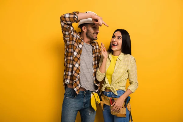 Trabajador feliz apuntando a colega mujer en amarillo - foto de stock