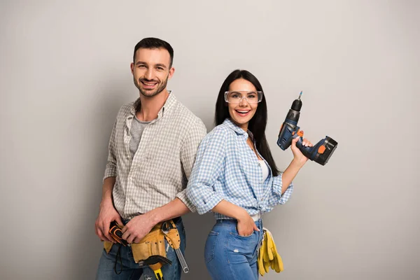 Protective manual workers holding electric drill on grey — Stock Photo