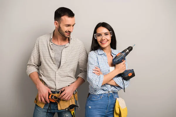 Operai protettivi che tengono trapano elettrico sul grigio — Stock Photo