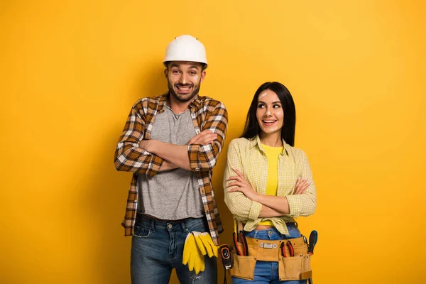 Trabalhadores manuais felizes com braços cruzados em amarelo — Fotografia de Stock