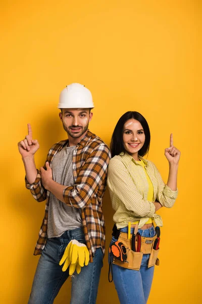 Trabalhadores manuais felizes tendo ideia e apontando para cima no amarelo — Fotografia de Stock