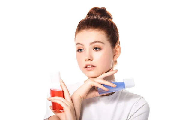 Tender teen girl holding two bottles with red and blue makeup removers, isolated on white — Stock Photo