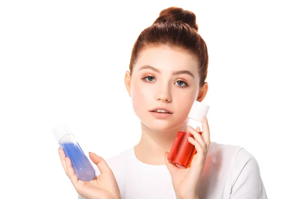 Attractive teen girl holding two bottles with red and blue makeup removers, isolated on white — Stock Photo