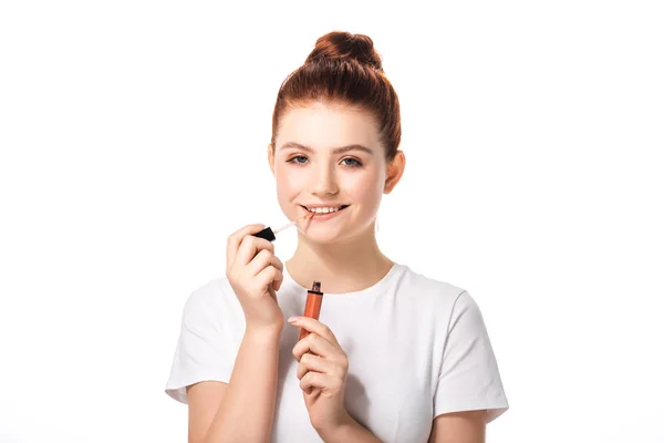 Belle adolescente souriante appliquant du brillant à lèvres, isolée sur du blanc — Photo de stock