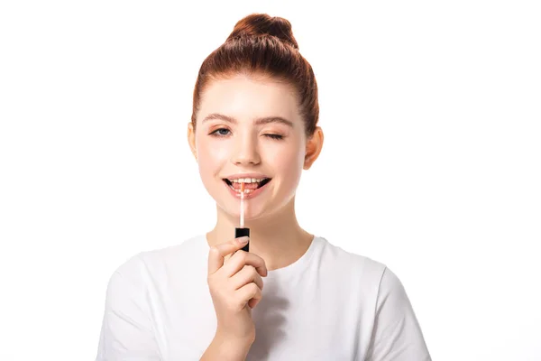 Glückliches Teenie-Mädchen zwinkert und trägt Lipgloss auf, isoliert auf weiß — Stockfoto