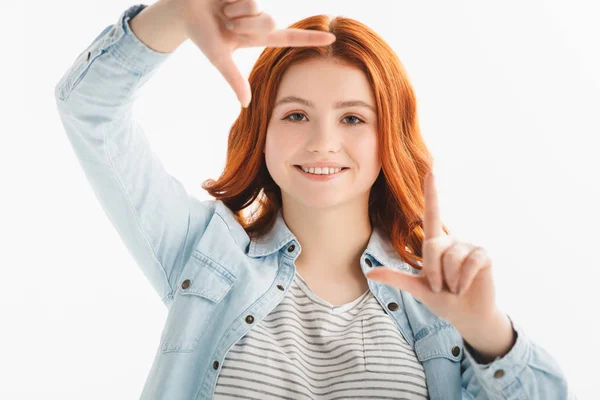 Lächelnde rothaarige Teenagerin zeigt Rahmen aus Händen, isoliert auf weiß — Stockfoto