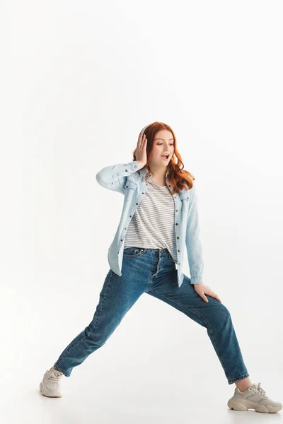 Excitada chica adolescente bailando y escuchando música con auriculares, aislada en blanco - foto de stock