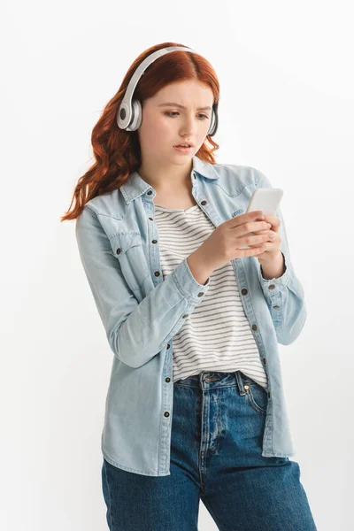 Hermosa chica adolescente escuchando música con auriculares y el uso de teléfono inteligente, aislado en blanco - foto de stock