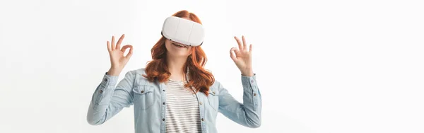 Plano panorámico de adolescente feliz que muestra signos de ok y el uso de auriculares de realidad virtual, aislado en blanco — Stock Photo