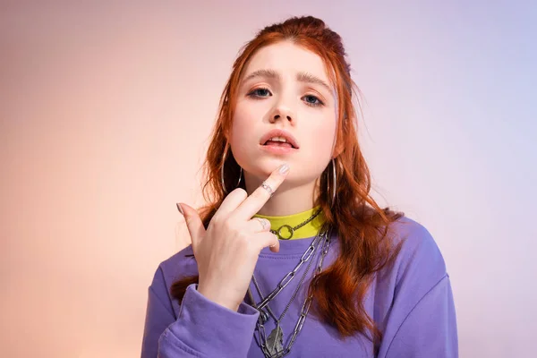 Female teenager in bad mood showing middle finger, on purple and beige — Stock Photo