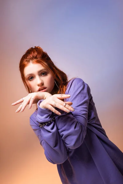 Красива нудна руда дівчина-підліток жестикулює на фіолетовому і бежевому — стокове фото