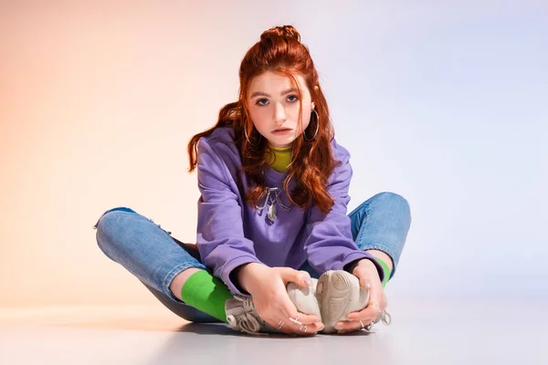 Beautiful bored teen girl sitting on purple and beige — Stock Photo