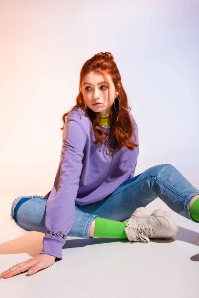 Приваблива нудна дівчина-підліток сидить на фіолетовому і бежевому — стокове фото