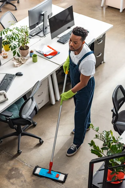 Vista ad alto angolo del pavimento di lavaggio africano americano con mop in ufficio — Foto stock