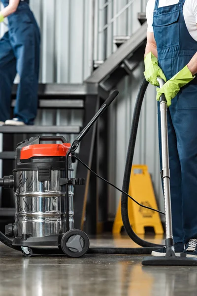 Cropped view of cleaner vacuuming floor near colleague cleaning stairs — Stock Photo