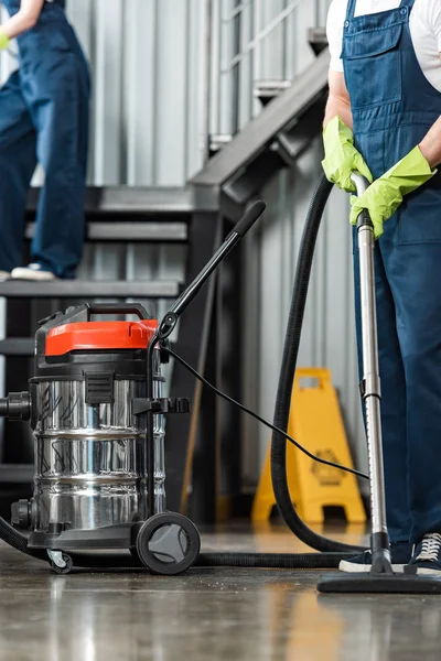 Vue recadrée du nettoyeur aspirateur près d'un collègue nettoyage des escaliers — Photo de stock