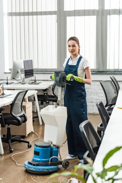 Attractive cleaner washing floor in open space office with cleaning machine — Stock Photo